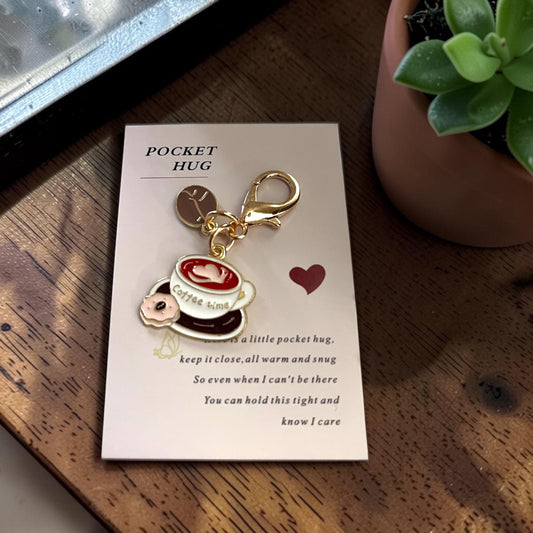 Pocket hug Keychain with a coffee-themed design on a card, placed on a wooden surface, unique keychain, pocket hug in Windsor Ontario. unique gift