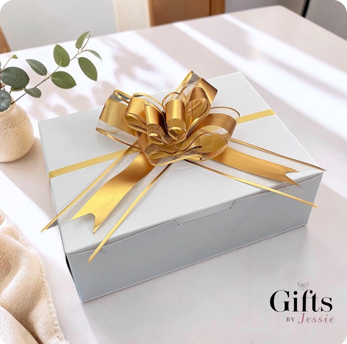 showing a white boxed gift with gold bow