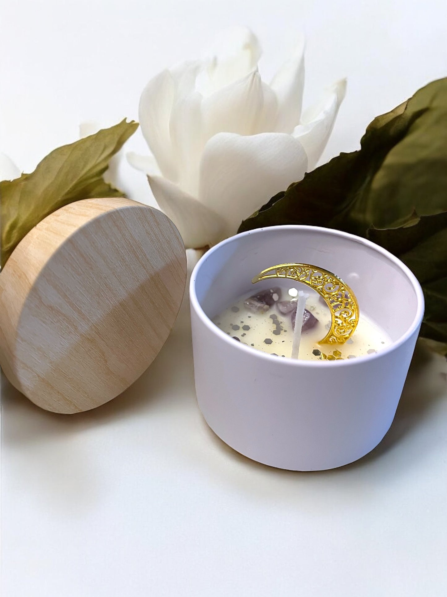 Candle in a white bowl with a wooden lid, surrounded by white flowers on a light background, with 'Mystical Moon' text. handmade unique candle with keepsake moon necklace pendant made in canada