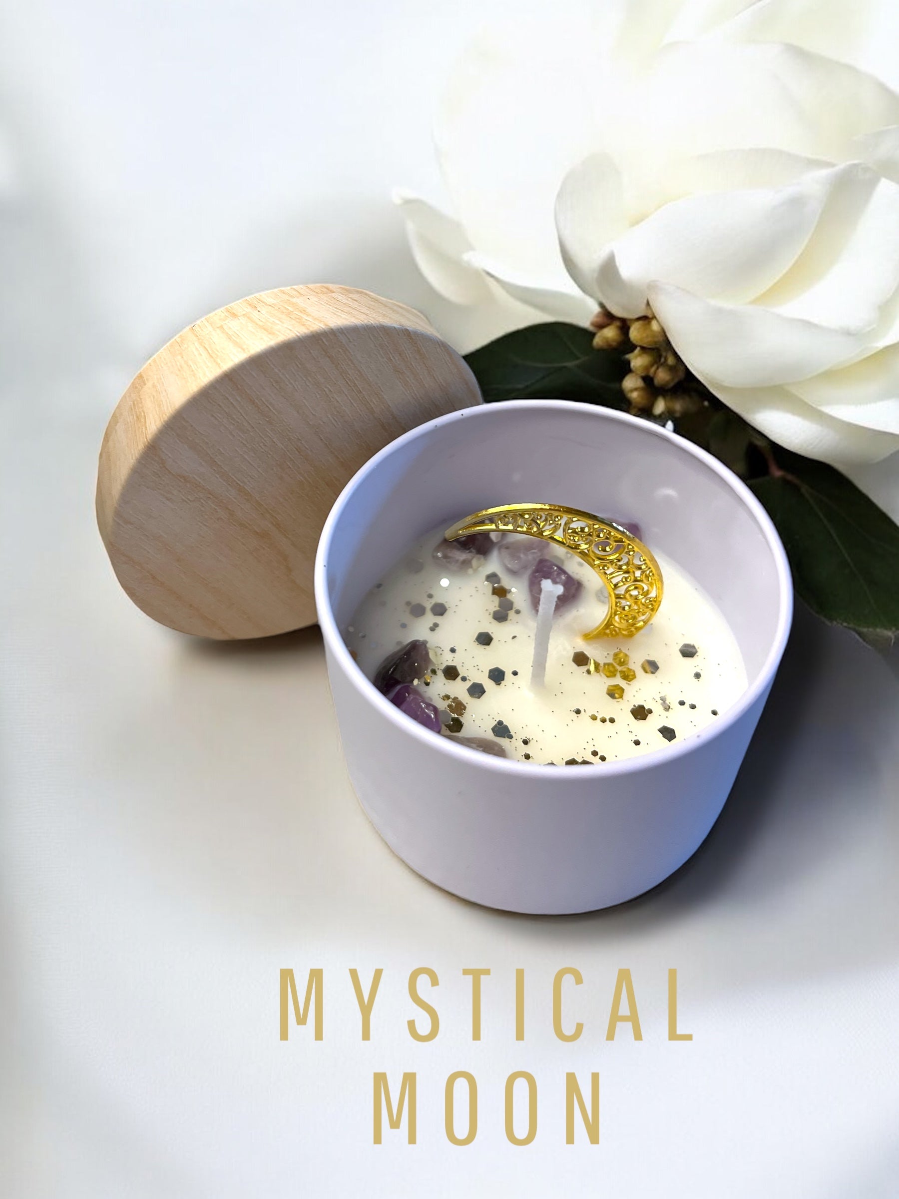 Candle in a white bowl with a wooden lid, surrounded by white flowers on a light background, with 'Mystical Moon' text. handmade unique candle with keepsake moon necklace pendant made in canada